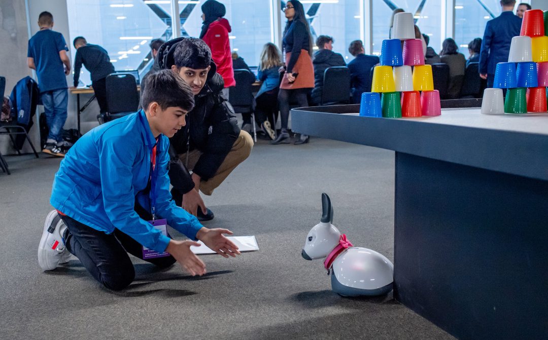 Two students playing with a MiRo robot
