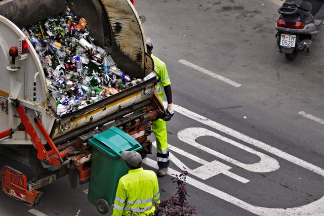 refuse workers loading a refuse truck with rubbish
